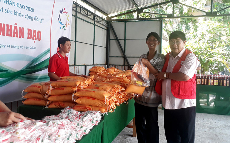 Ông Huỳnh Tấn Tịnh, Chủ tịch Hội Chữ thập đỏ tỉnh hướng dẫn người dân nghèo đến nhận nhu yếu phấm tại các gian hàng miễn phí. Ảnh: NGỌC DUNG