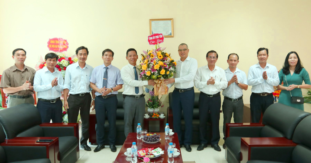 Đồng chí Phạm Đại Dương tặng hoa, chúc mừng các thầy, cô giáo Trường đại học Xây dựng Miền Trung - Ảnh: HÀ MY