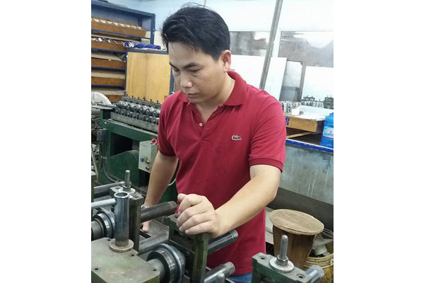 Anh Nguyễn Văn Tháp đang điều khiển máy dập kim loại - Ảnh: NGỌC HÂN
