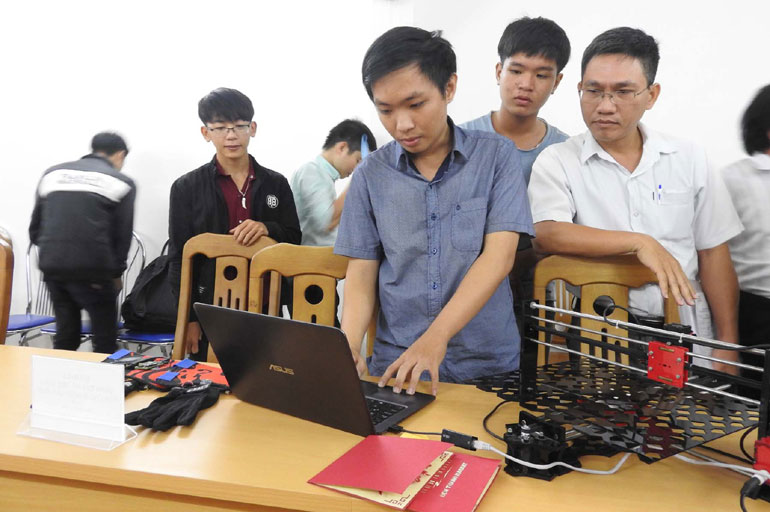 Ngô Huỳnh Ngọc Khánh (bên máy tính) giới thiệu giải pháp Máy cắt laser công nghệ IoT đến ban giám khảo - Ảnh: THÁI HÀ