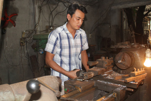 Đặng Ngọc Tiến đang gia công máy móc cho nông dân tại cơ sở làm việc của mình