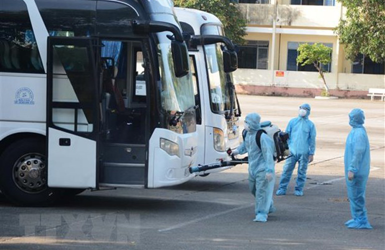 Nhân viên y tế phun thuốc khử trùng vào xe chở công dân từ Hàn Quốc trở về. Ảnh: TTXVN