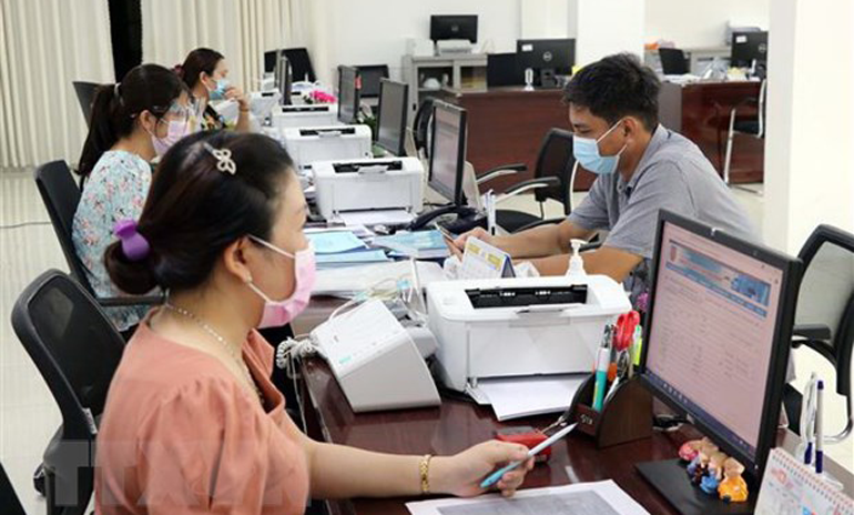 Cán bộ công chức Trung tâm Phục vụ hành chính công tỉnh Ninh Thuận giải quyết hồ sơ, thủ tục hành chính cho các doanh nghiệp. Ảnh: TTXVN