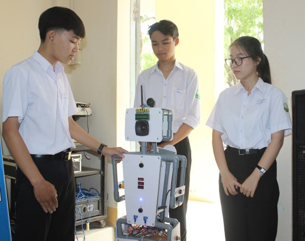 Ba em học sinh: Long Nhật, Xuân Bách và Long Thưởng (từ trái sang) kiểm tra hoạt động của robot AI FBM. Ảnh: LỆ VĂN